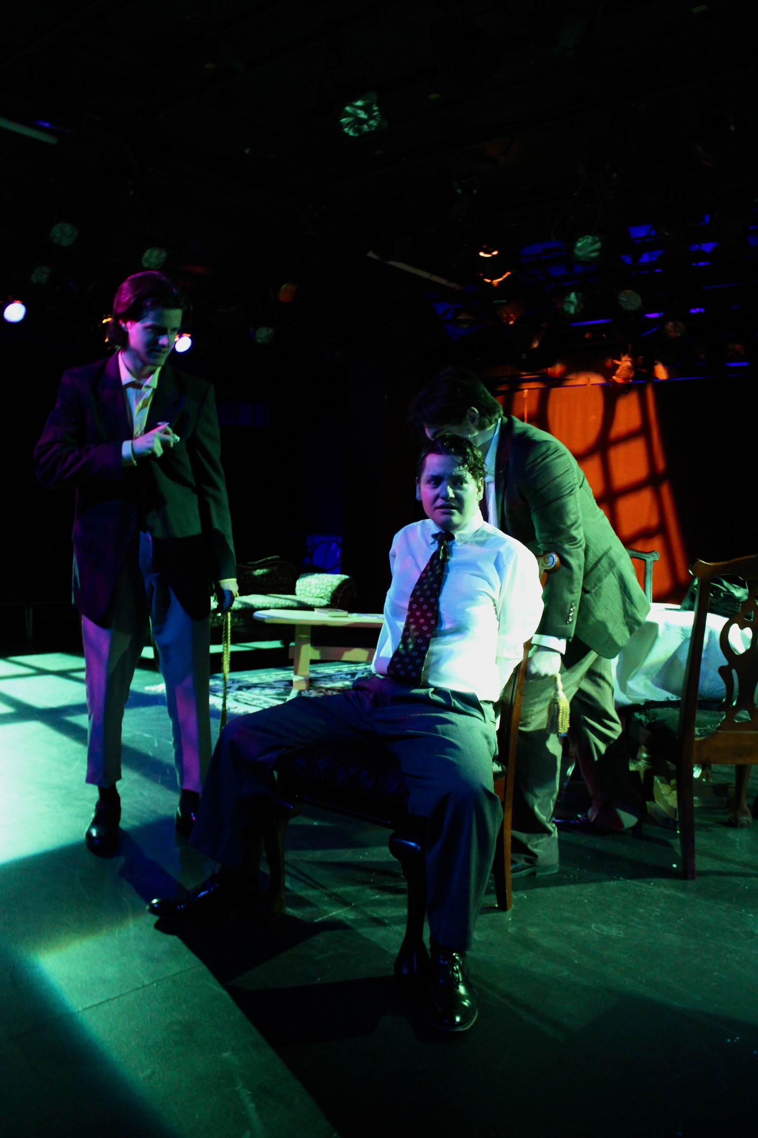 Tobias Sanders as Mortimer Brewster being tied up with Jack Williams as Dr. Einstein and Tyler Radze as Jonathan Brewster in Second Stage Productions "Arsenic and Old Lace" in creepy lighting