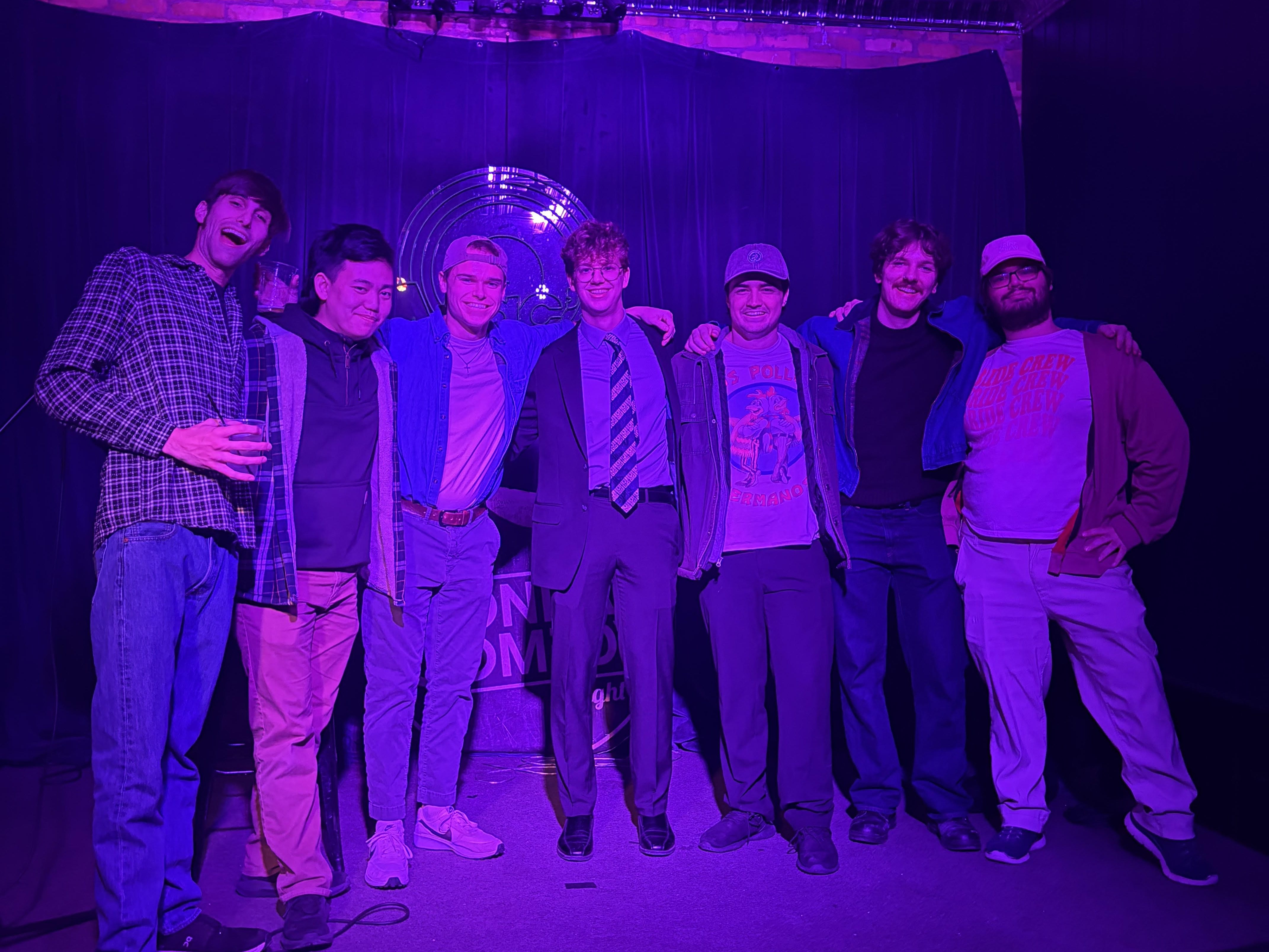 Karam Mawazini, Kyle Angelino, Logan Verlinde, David Meagher, Tyler Radze, Tyler Finch, and Anthony Monteleone on the stage of Mac's Bar in East Lansing