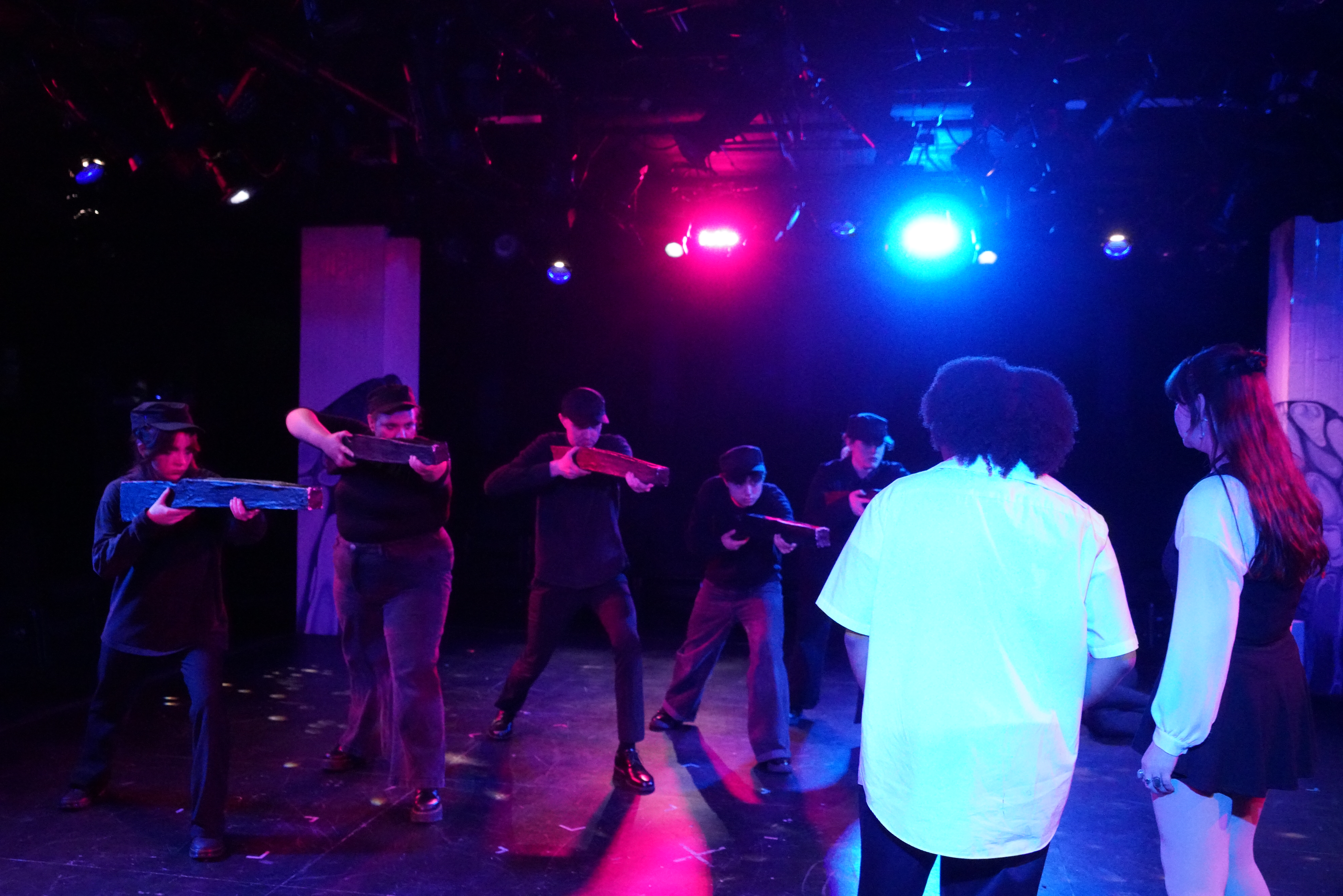 A group of PEIP soldiers with twirling guns trained on August Garret playing Paul in America is Great Again in Second Stage Productions "The Guy Who Didn't Like Musicals"