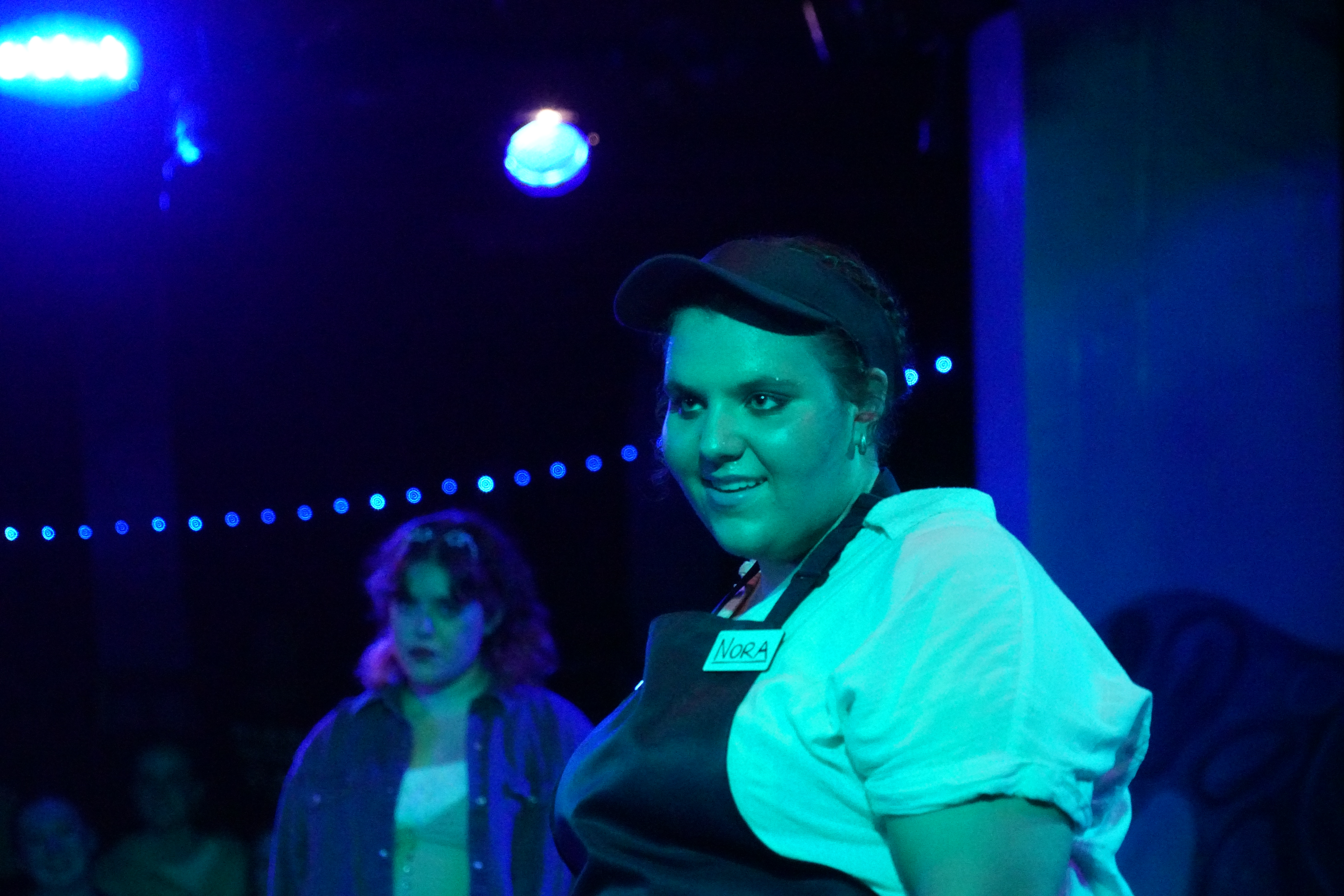 Casey Fosbenner as Nora with Sophia Catella as Greenpeace Canvasser in background in Second Stage Productions "The Guy Who Didn't Like Musicals"